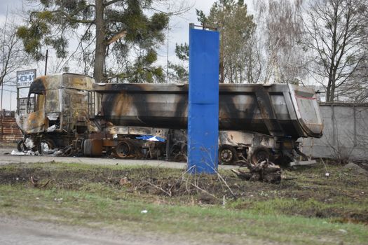 A heavily damaged and burnt truck left abandoned in a city street, creating a scene of destruction.