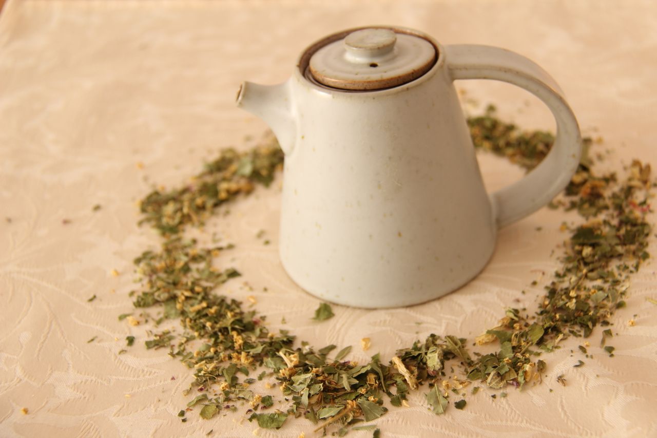 minimalist ceramic teapot surrounded by a heart of dried herbs perfect