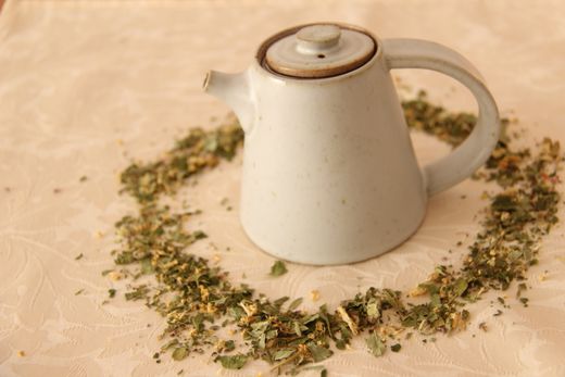 Stoneware teapot ringed by loose dried herbs — photo by Jakob Welik on Pexels