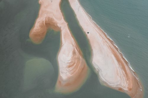 Free A mesmerizing aerial view of a sandy peninsula surrounded by calm ocean waters, taken from above. Stock Photo