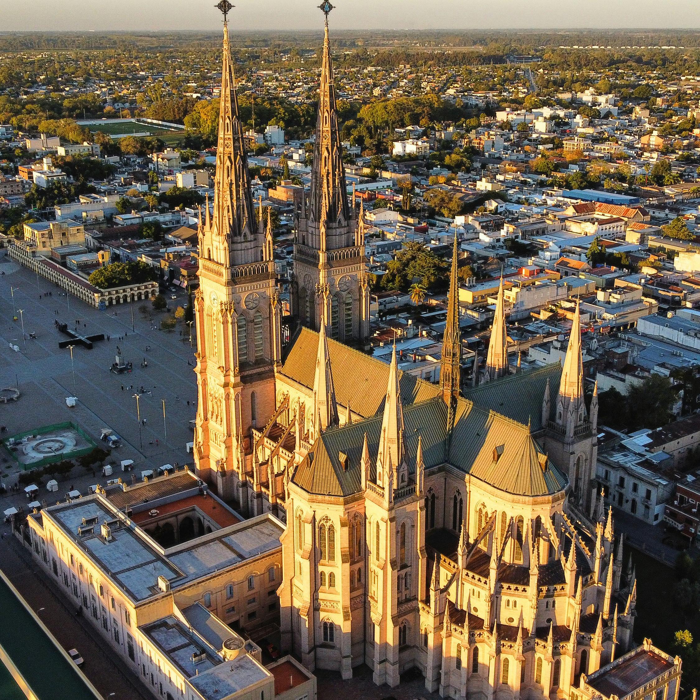 Stunning aerial shot of the Gothic Basilica of Our Lady of Luján in Buenos Aires, Argentina, bathed in golden sunset light.