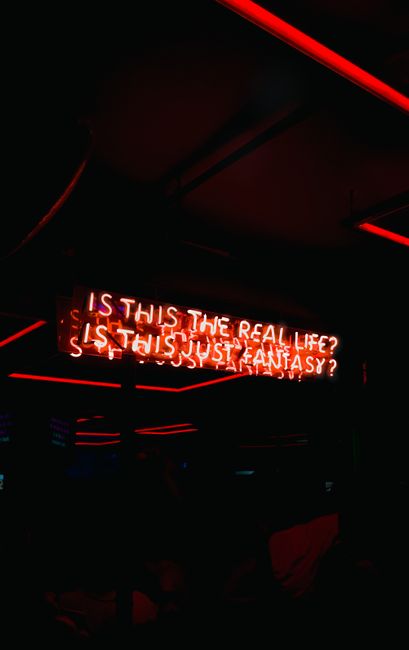 Red neon sign displaying famous lyrics in a dimly lit club setting, exuding a moody atmosphere.