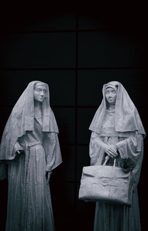 Free Graceful stone nun statues showcased in an art exhibition with an elegant dark backdrop. Stock Photo