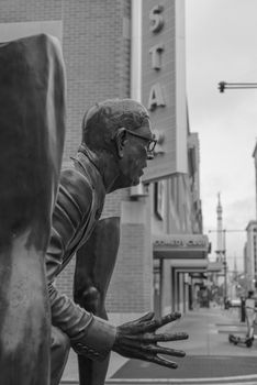 A dramatic black and white photo capturing an urban sculpture against a city backdrop.