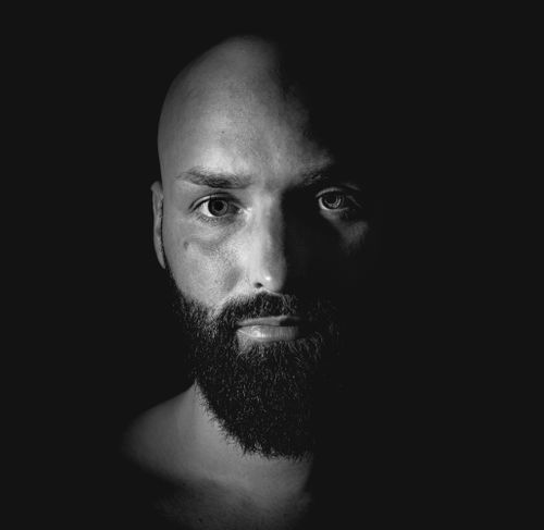 Free Close-up black and white portrait of a bald man with a beard, highlighting dramatic shading and facial features. Stock Photo