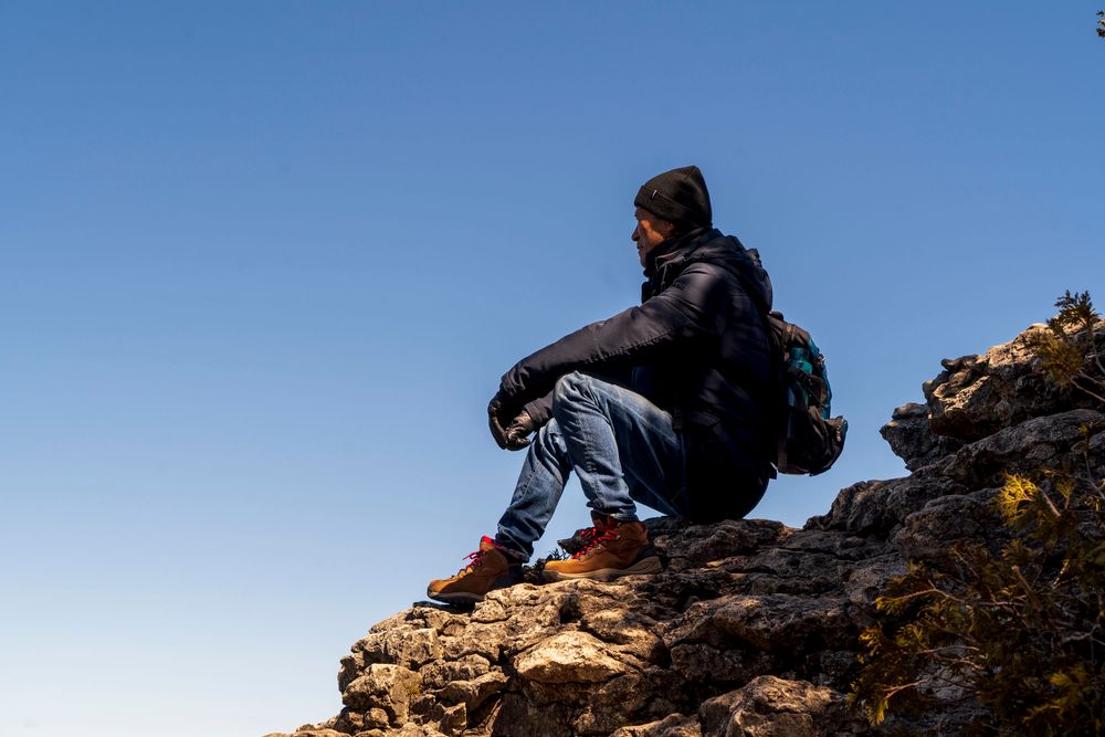 A backpacker resting on a rocky summit above the clouds