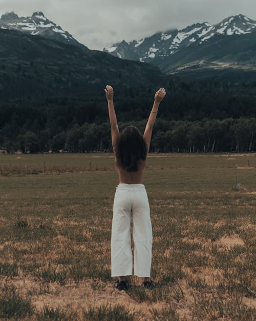 Free Woman Standing Shirtless and Raising Her Arms Stock Photo
