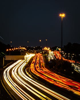 A stunning long exposure capture of cars on an urban highway at night, showcasing light trails.