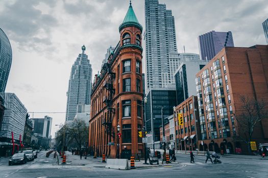 View of the iconic Flatiron Building amidst Toronto's urban skyline on a cloudy day.