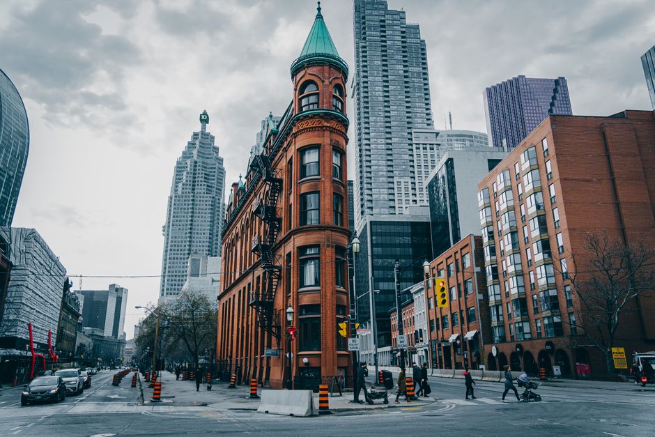 View of the iconic Flatiron Building amidst Toronto's urban skyline on a cloudy day.