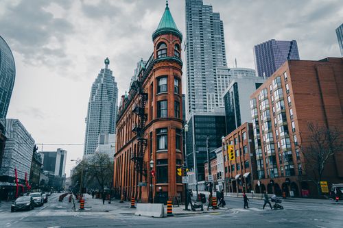 Free View of the iconic Flatiron Building amidst Toronto's urban skyline on a cloudy day. Stock Photo