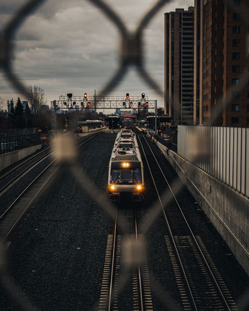 Free Passenger train on city railway through urban landscape with high-rise buildings. Stock Photo