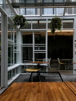 Contemporary café with a modern interior design featuring wooden tables and greenery.