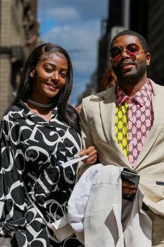 Elegant couple in fashionable attire posing confidently in urban setting.