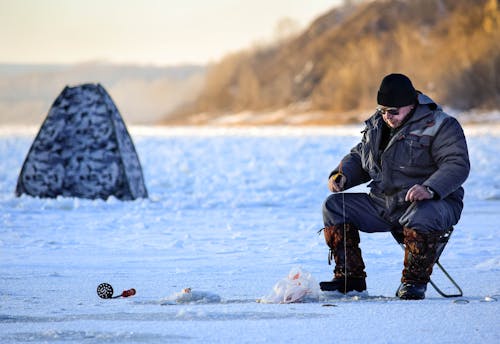 Man Sitting on a Frozen Lake and Fishing 