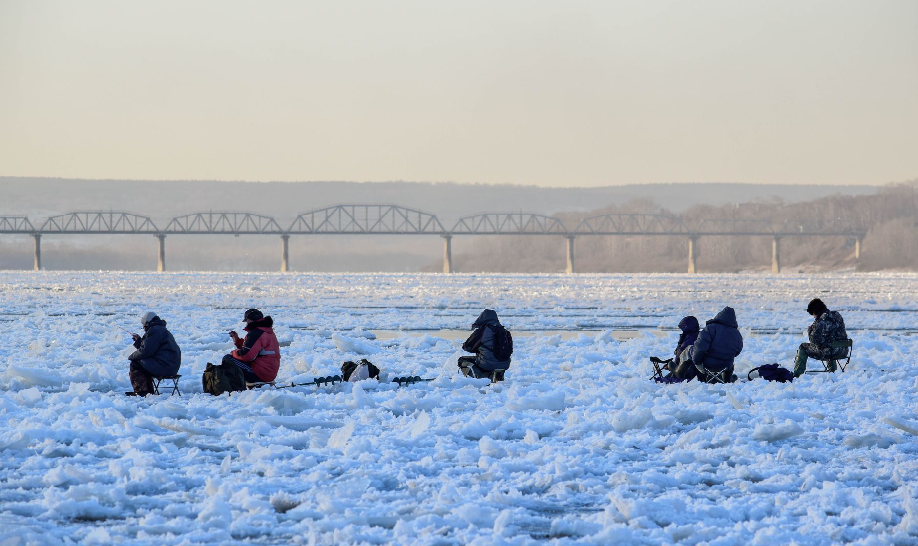 Group of people ice fishing on a frozen river in Kemerovo, Russia.