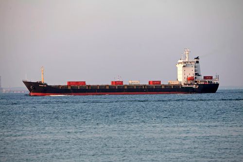 Free Cargo ship carrying containers on a calm sea under a gray sky. Stock Photo