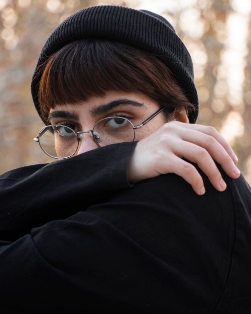 Free Intriguing close-up portrait of a person with eyeglasses and knit hat in natural setting. Stock Photo