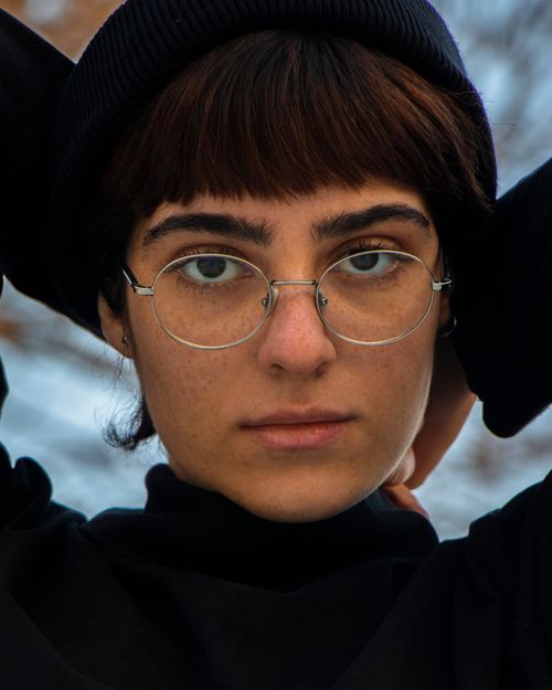Free Close-up portrait of a woman wearing glasses and a beanie, exuding modern style. Stock Photo