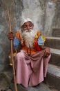 Man in Red and Yellow Robe Sitting on Brown Wooden Chair