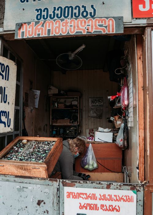Free A cozy market stall featuring a merchant surrounded by colorful items. Ideal for cultural themes. Stock Photo