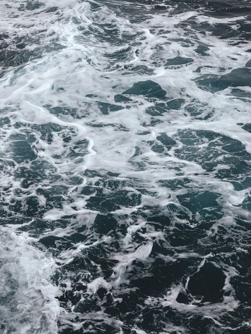 Free A captivating aerial view of ocean waves in motion, showcasing foam and intricate water patterns. Stock Photo