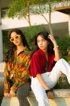 Two fashionable teenagers posing outdoors in vibrant clothing and sunglasses.