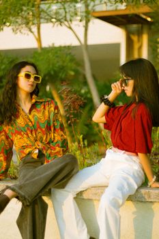Stylish teenagers posing confidently in vibrant outfits and sunglasses outdoors.
