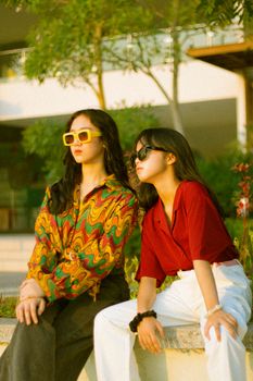 Two young women wearing stylish sunglasses, enjoying the outdoors under bright sunlight.