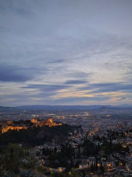 A stunning evening cityscape of Granada featuring the illuminated Alhambra under a beautiful twilight sky.
