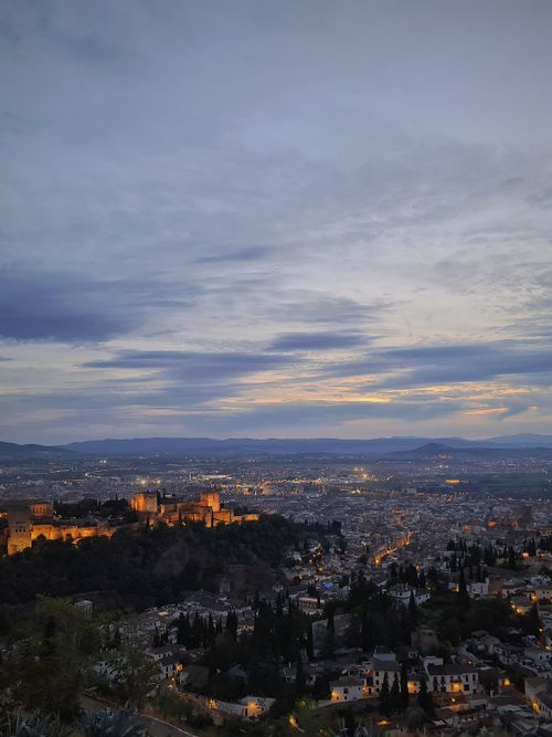 Free A stunning evening cityscape of Granada featuring the illuminated Alhambra under a beautiful twilight sky. Stock Photo