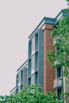 Low angle view of a modern apartment building with brick facade and lush greenery.