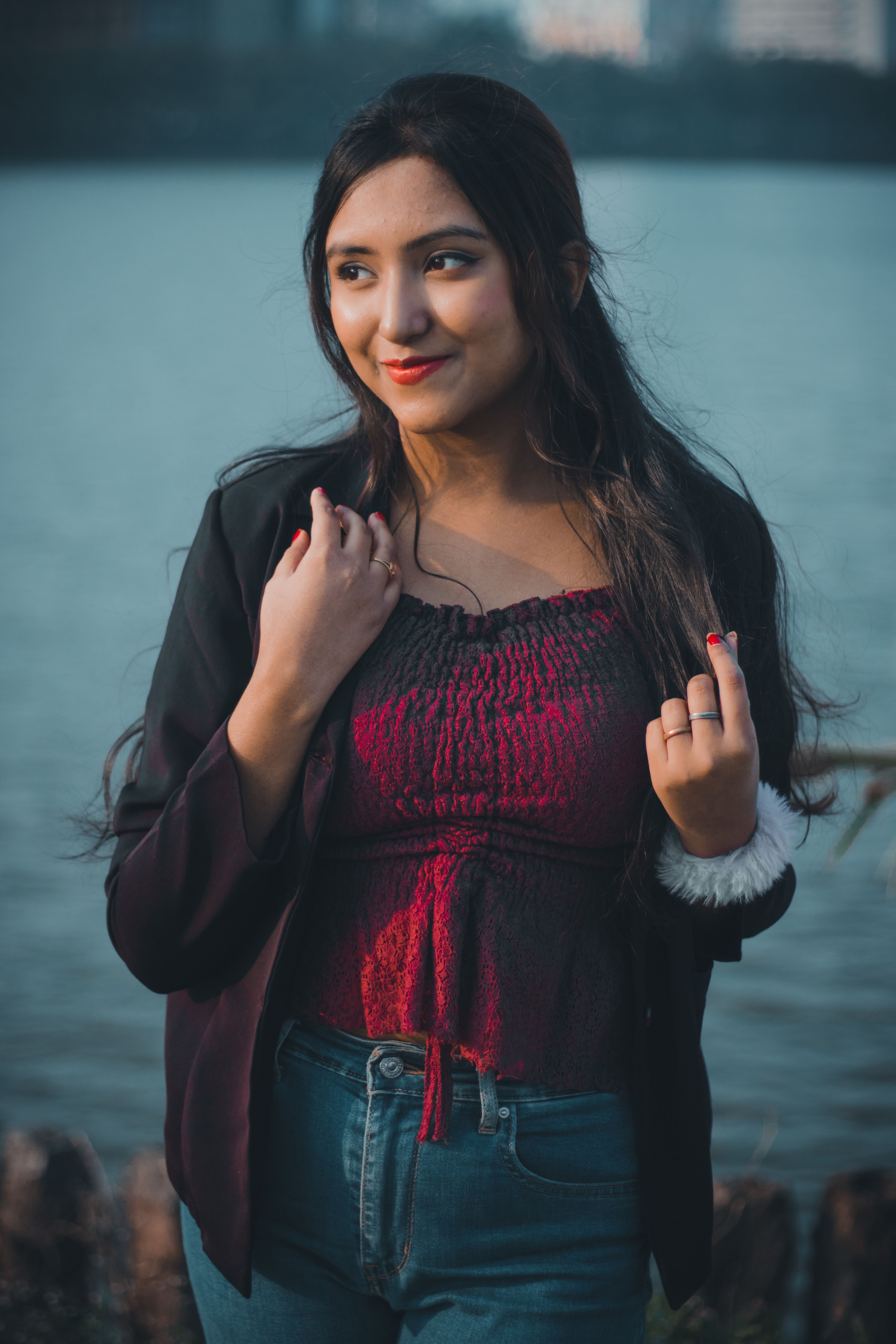Charming portrait of a young woman in stylish attire standing by a serene waterfront in Kolkata, India.