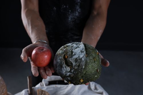 Free A close-up of hands holding an apple and artisan bread, showcasing contrast and texture. Stock Photo