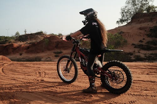 Free Woman in Black Jacket Riding Motocross Dirt Bike on Brown Field Stock Photo