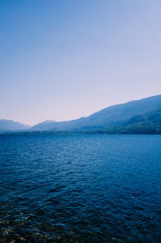 A calm ocean scene with distant mountains under a clear blue sky, offering a tranquil and scenic view.