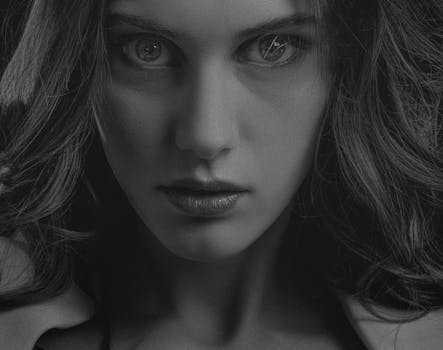 Close-up black and white portrait of a serious woman with intense gaze, focusing on her eyes.