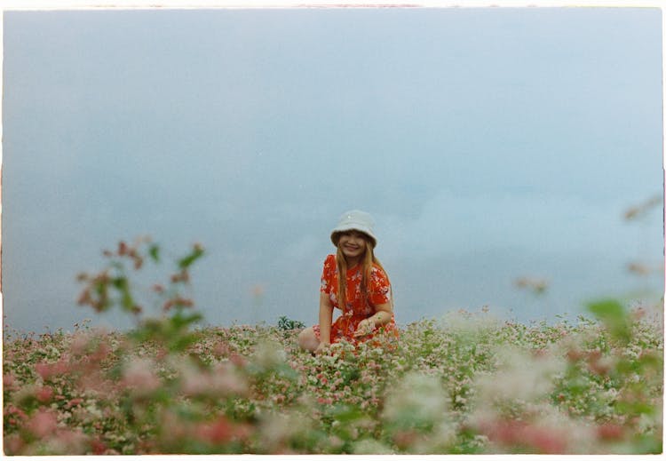 Woman In Floral Dress Squatting On Flower Field