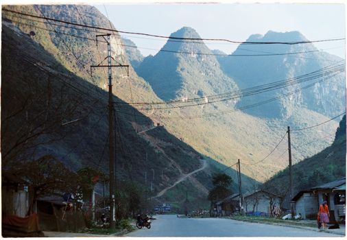 A tranquil mountain village road surrounded by majestic peaks and nature.