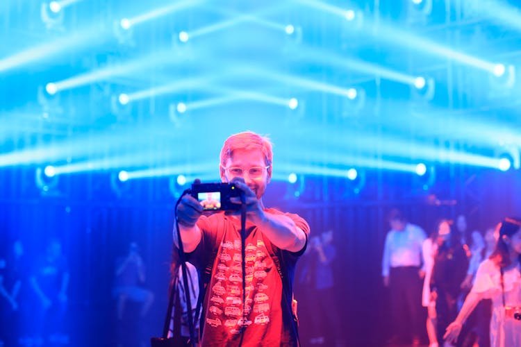 Smiling Man Making Self-Portrait Picture On Camera At Concert