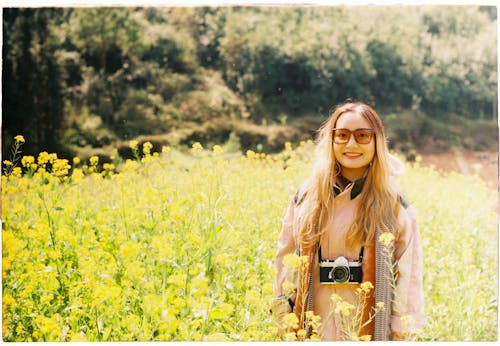 Woman Wearing Sunglasses With Camera Smiling on Grass Field 