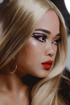 Close-up of a glamorous woman with artistic makeup and blonde hair, showcasing elegance and style.