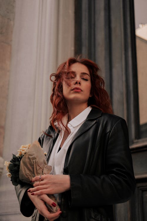 Woman in Black Leather Jacket Holding Bouquet of Flowers