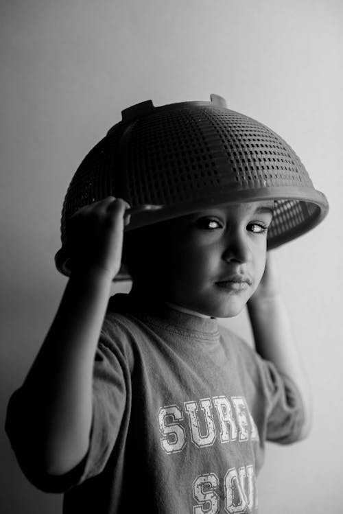 Grayscale Photo of a Kid with Strainer on the Head