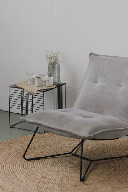 A minimalist interior featuring a sleek gray chair, woven rug, and modern side table.