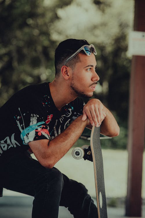 Man in Black Crew Neck T-shirt Holding Skateboard