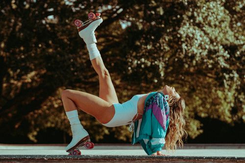 Free A woman performing an athletic pose on roller skates in an outdoor setting. Stock Photo