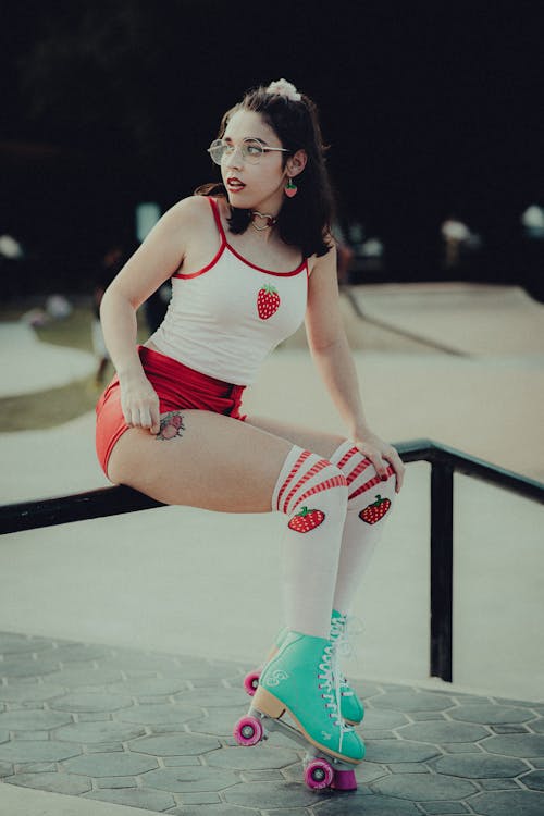 A woman in White Tank and Red Shorts is Sitting on Metal Bar