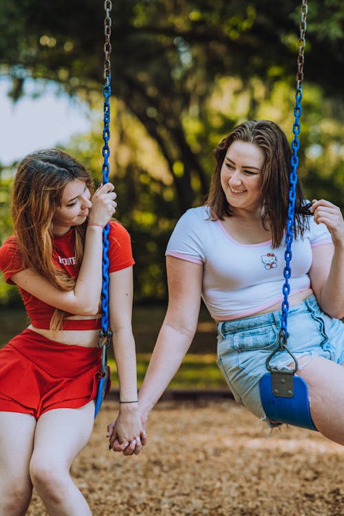 Smiling Women on a Swing Holding Hands