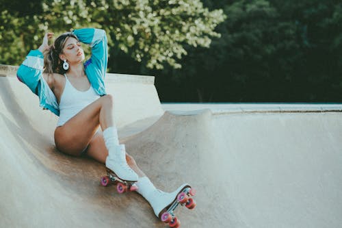Woman Wearing White Roller Skates Sitting on Skate Ramp